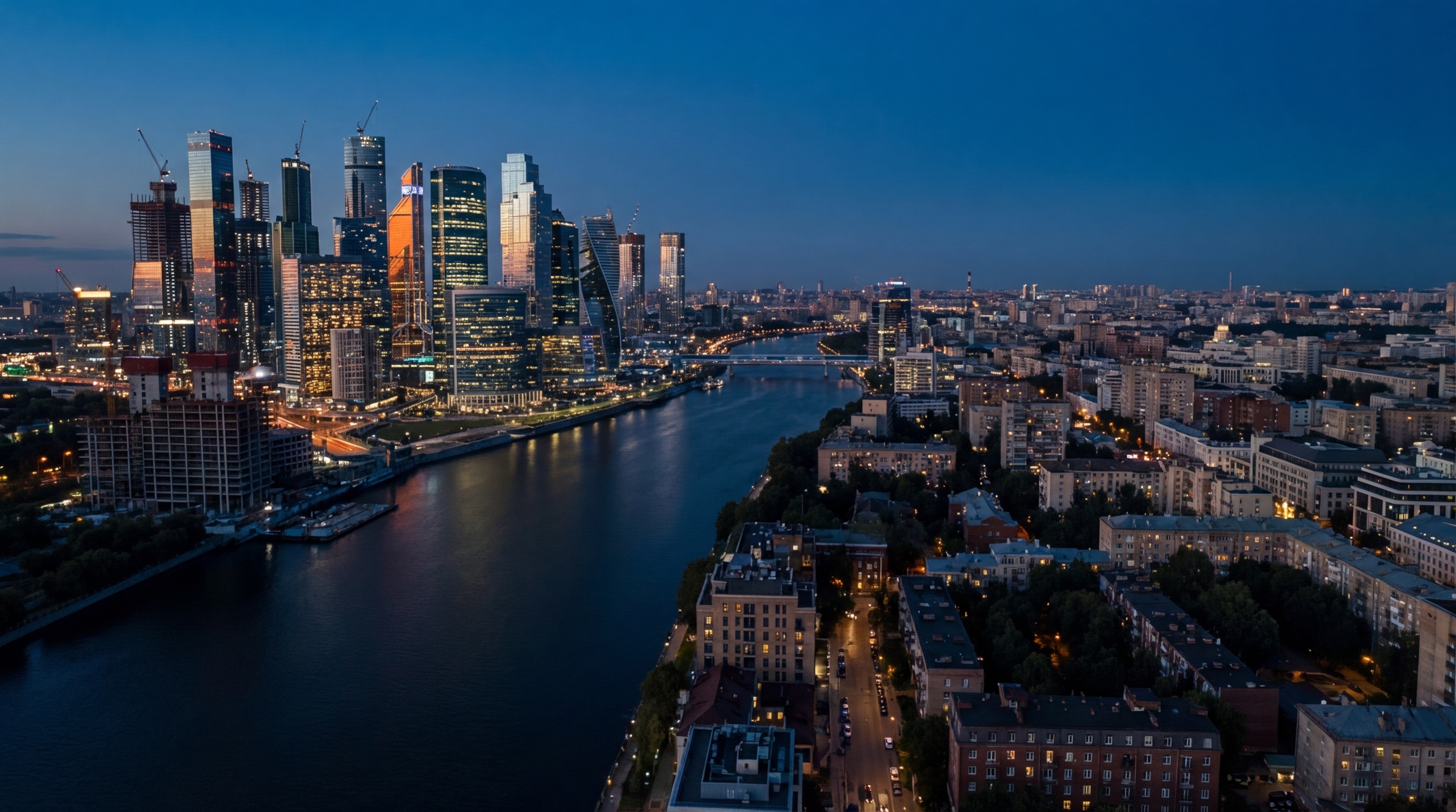 A city divided at dusk — one side rising with glass towers, the other quieter and contracting — two economies, one building